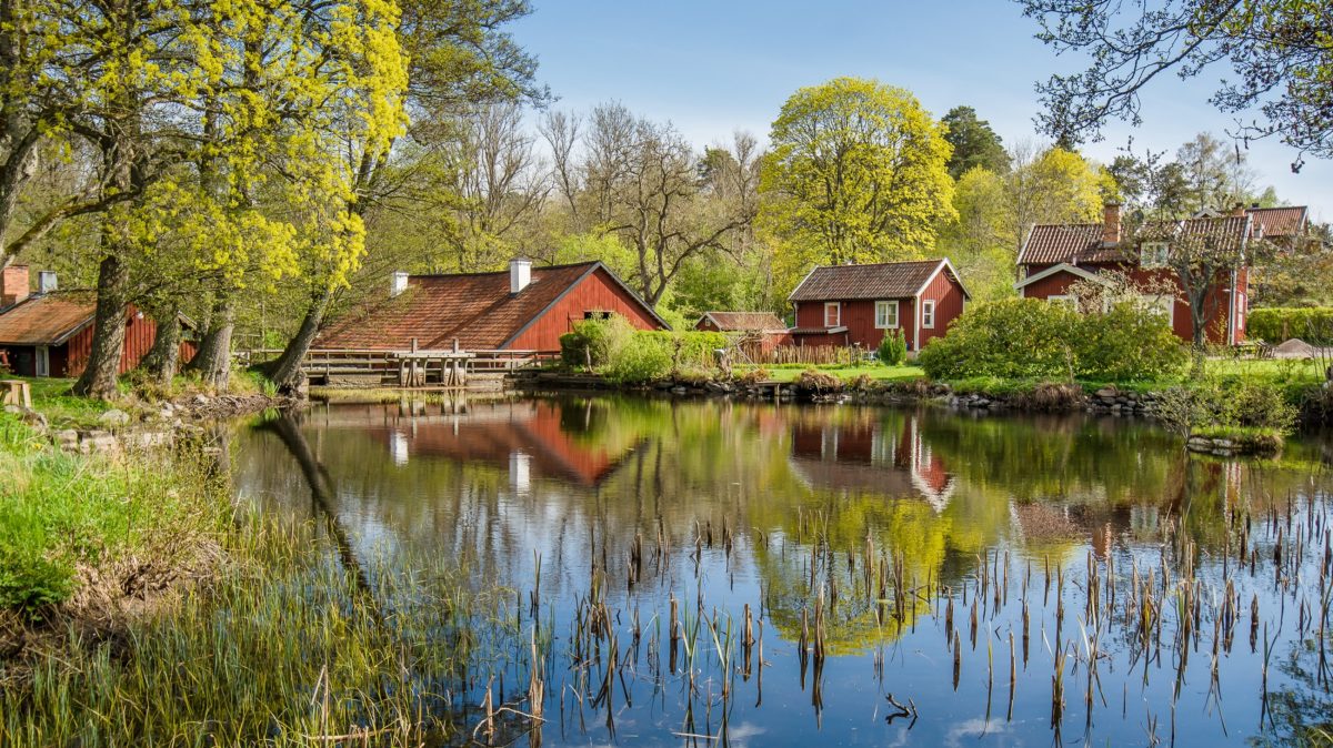 Old, red houses with green lawns and a serene lake